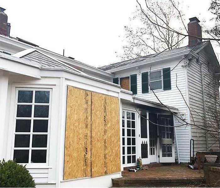 Exterior view of residential fire damage with board-up windows for security and mitigation