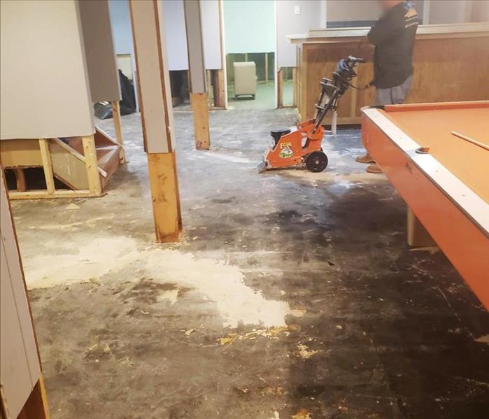 Residential basement water damage using equipment to remove wet flooring during repairs